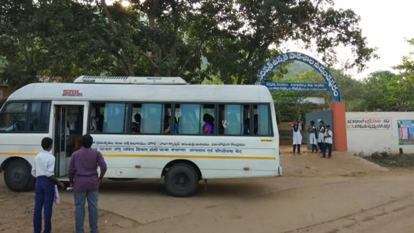 A white minibus parked near the entrance to an educational institution.