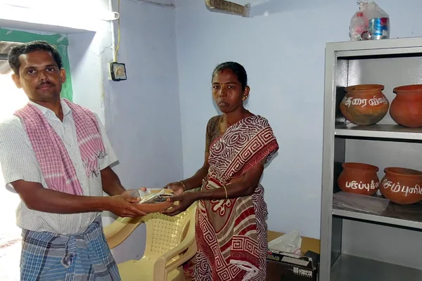 Two adults holding a seed packet together in a community room.