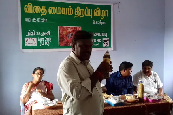 Adults speaking and listening during a meeting in a community room.