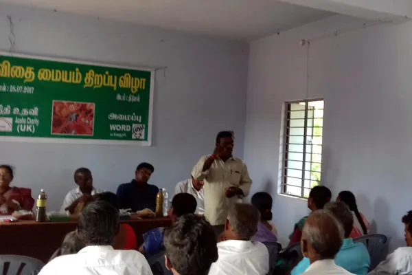 People gathered indoors for a discussion beside seed-storage displays.