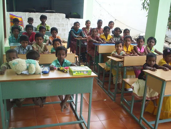 Students reading at classroom desks with a bookshelf behind them.